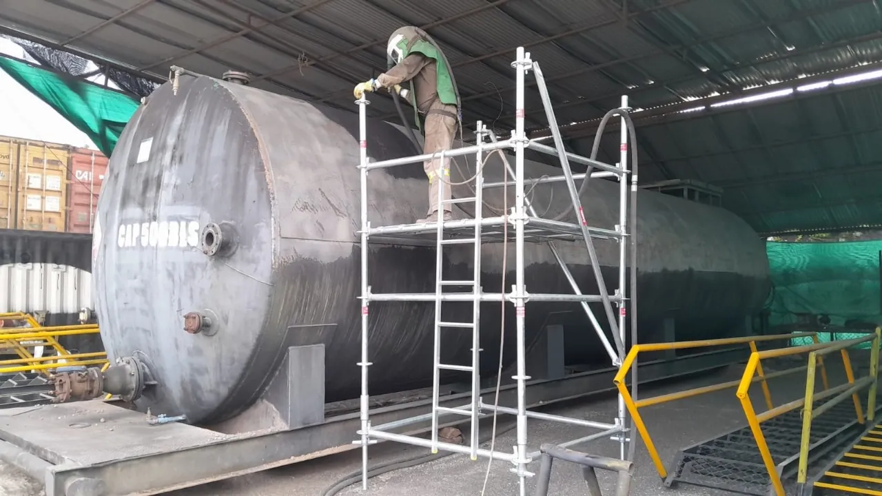 Operario de Alquiser aplicando sandblasting a un tanque cilíndrico de 500 barriles